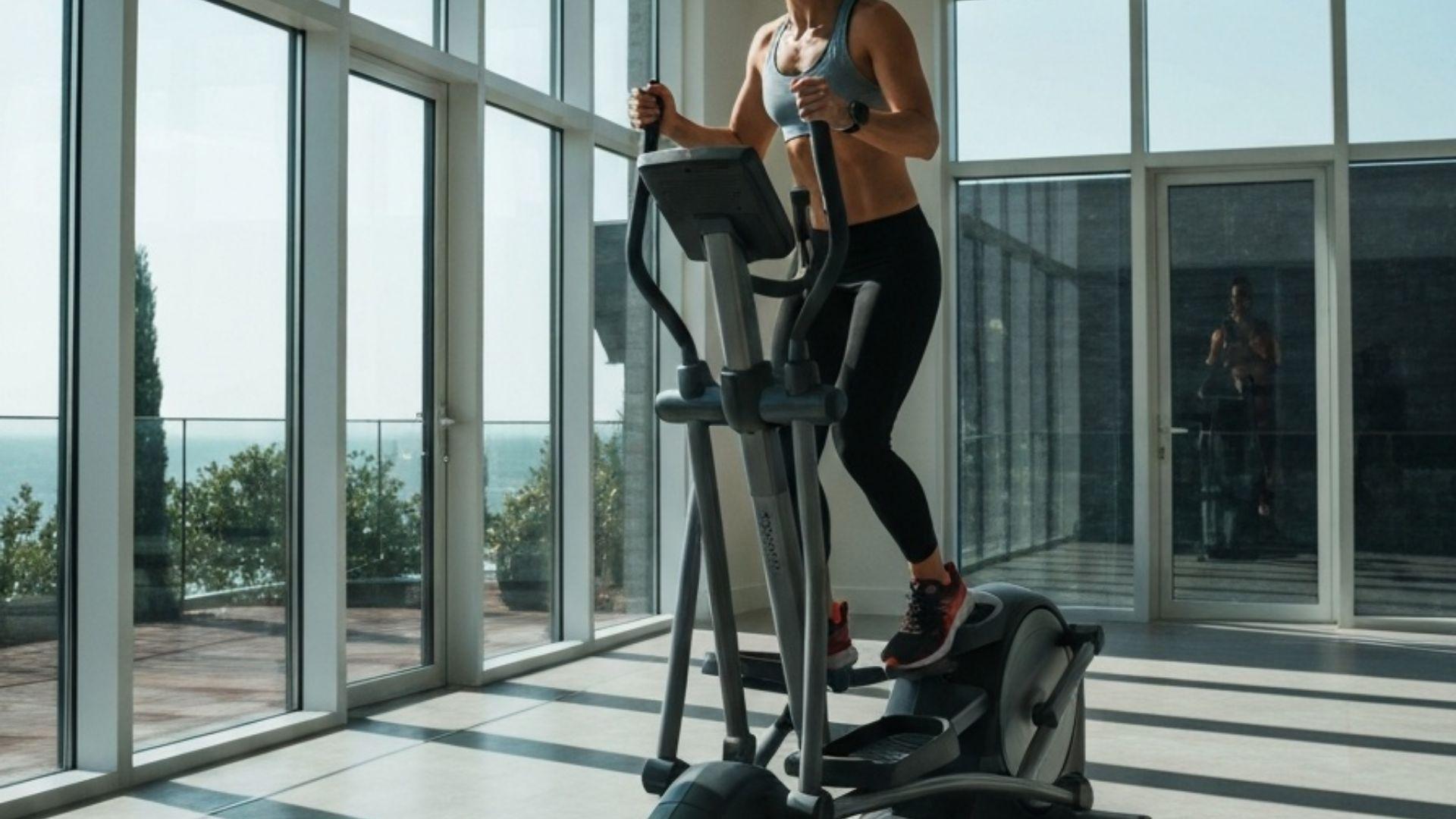 Person der træner på en crosstrainer i et lyst hjemmegym