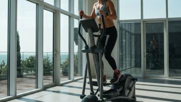 Person der træner på en crosstrainer i et lyst hjemmegym