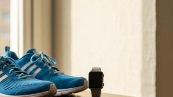 Smartwatch og letvægts løbesko på et lyst trærummmiljø